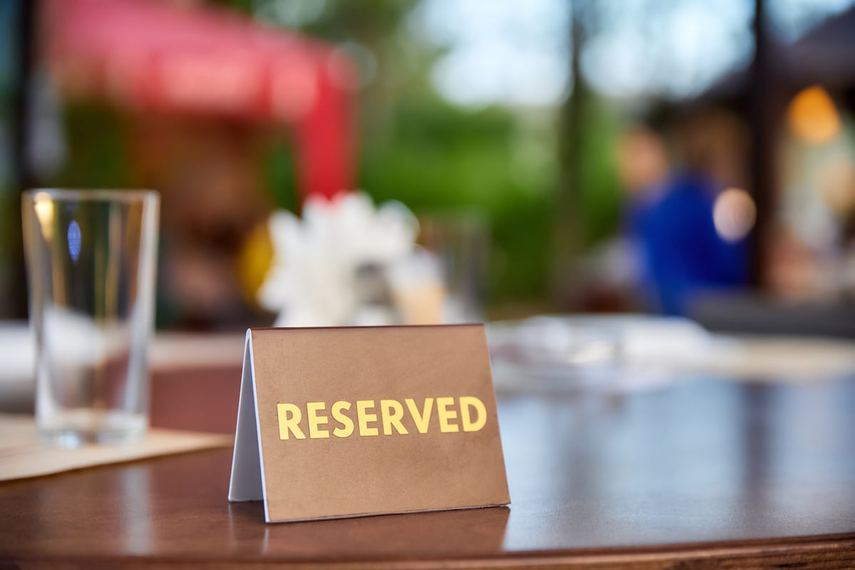 Plastic plaque with the inscription Reserved on the restaurant table.